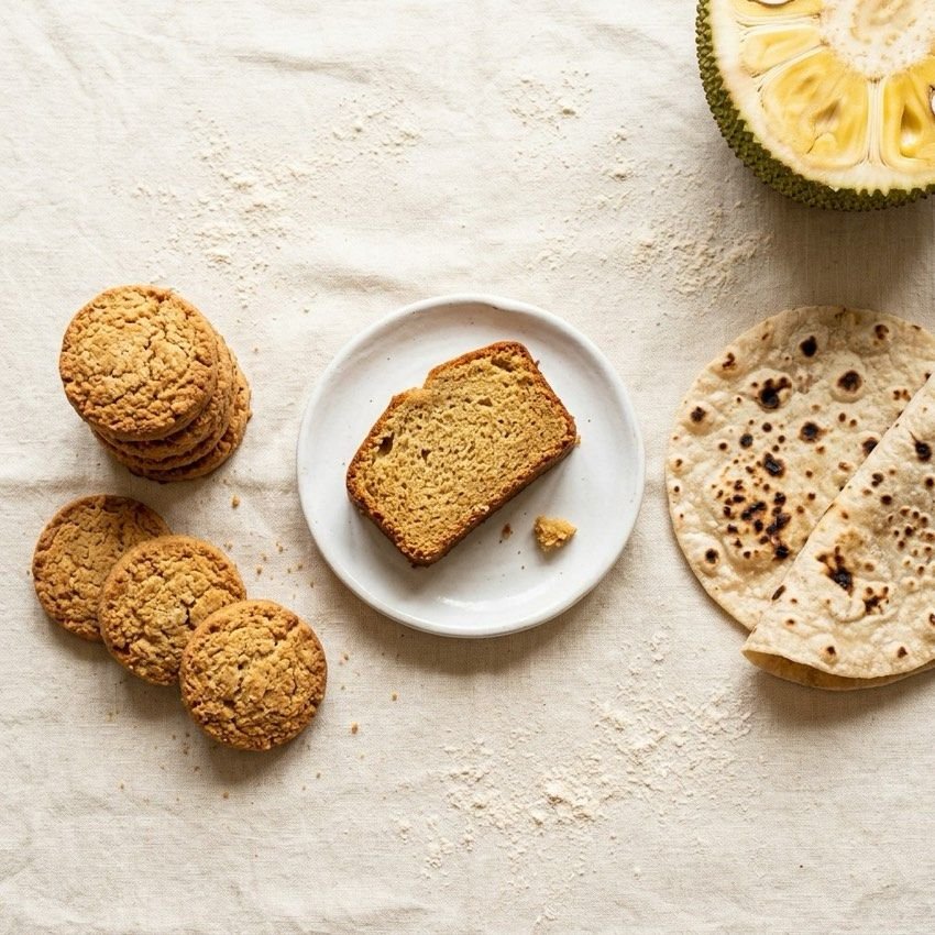 Jackfruit-flour biscuits, cake and flatbread beside a halved jackfruit